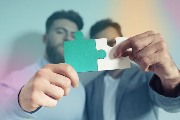 Men holding puzzle pieces that fits together