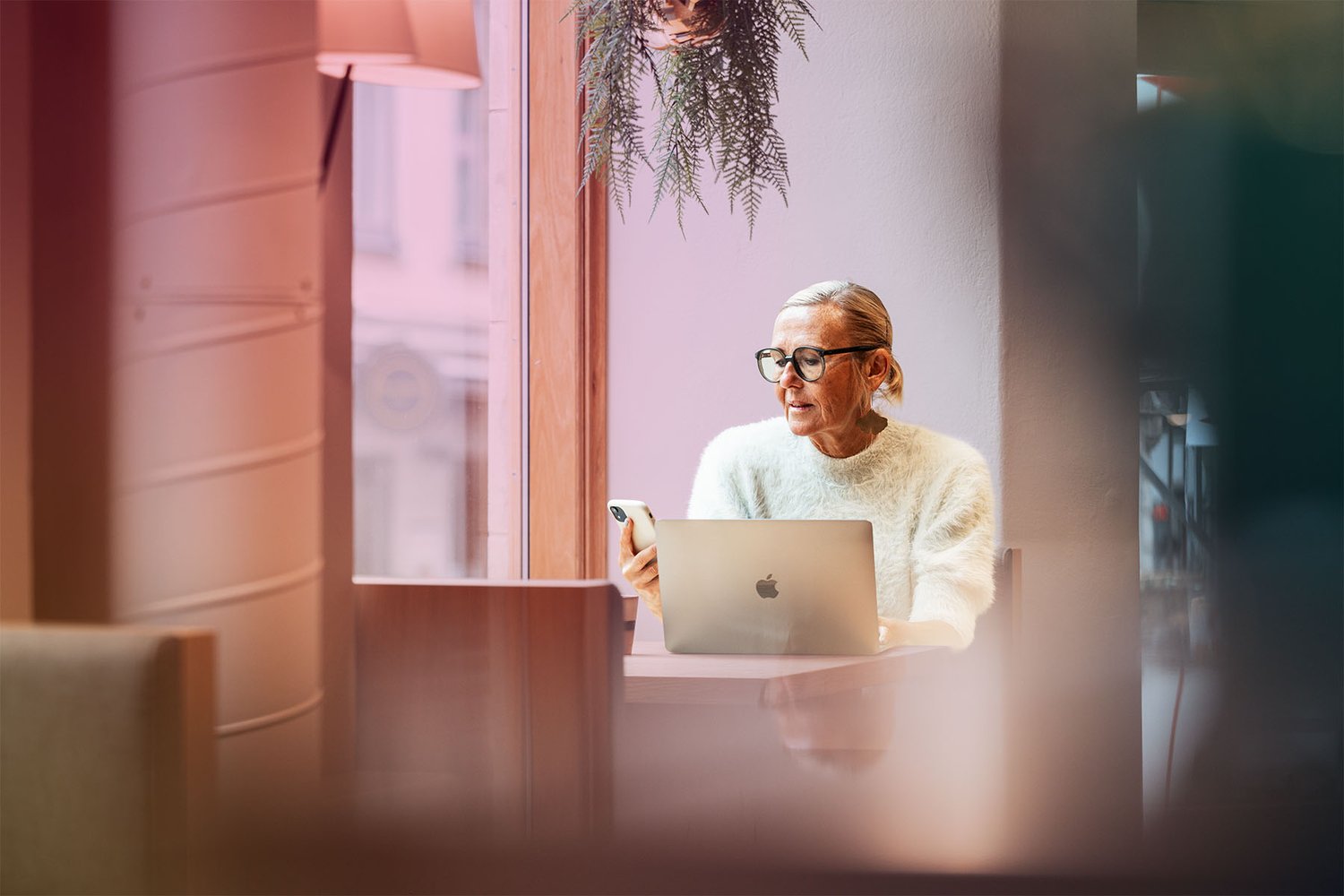 A woman working from a café with her laptop and mobile