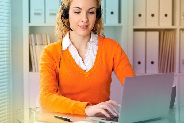 woman woking on a computer, with a headset on